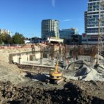 An excavator rests near a partially completed worksite for The Paramount development.